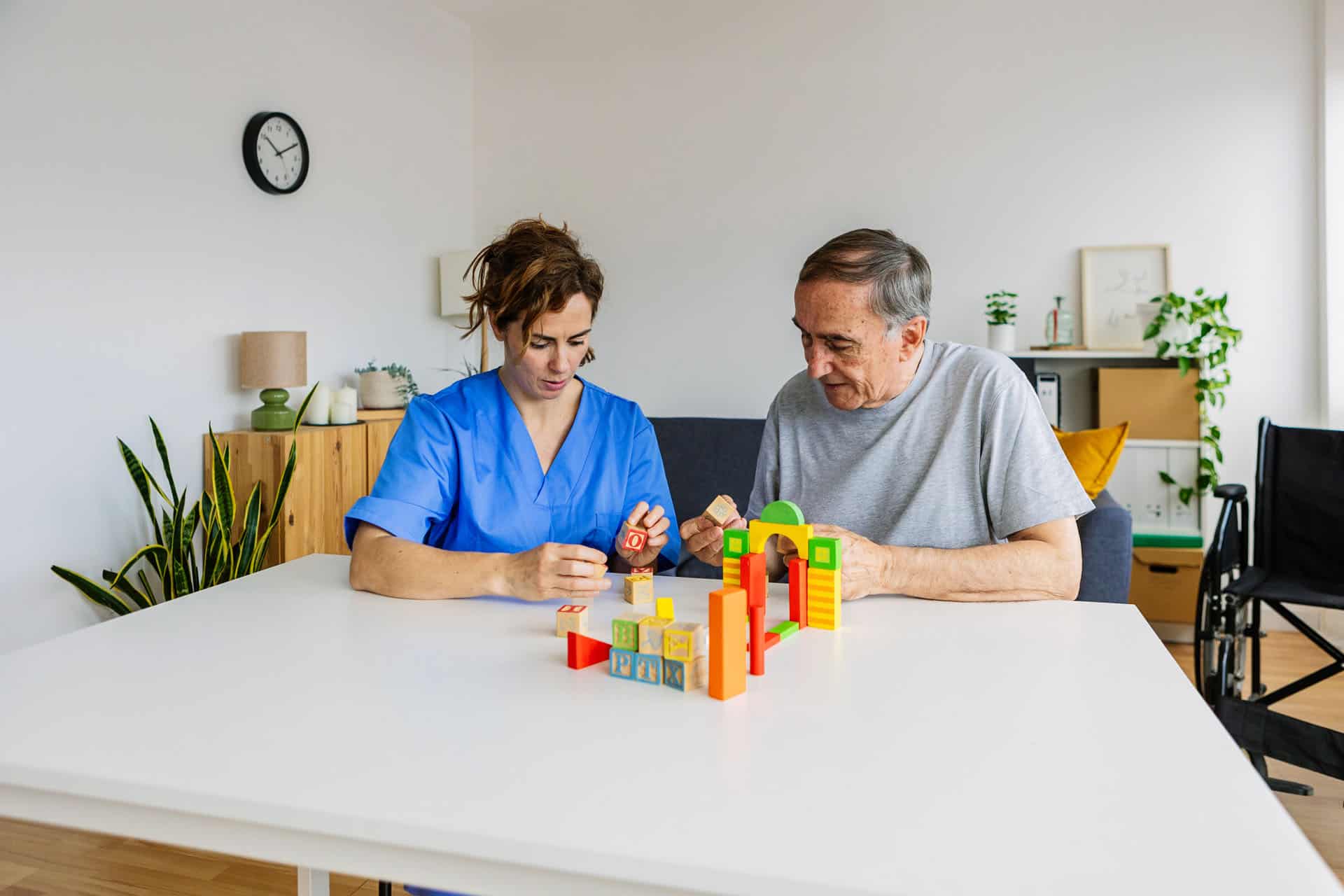 Occupational therapist helping an adult improve fine motor skills and hand coordination using building blocks during a therapy session.