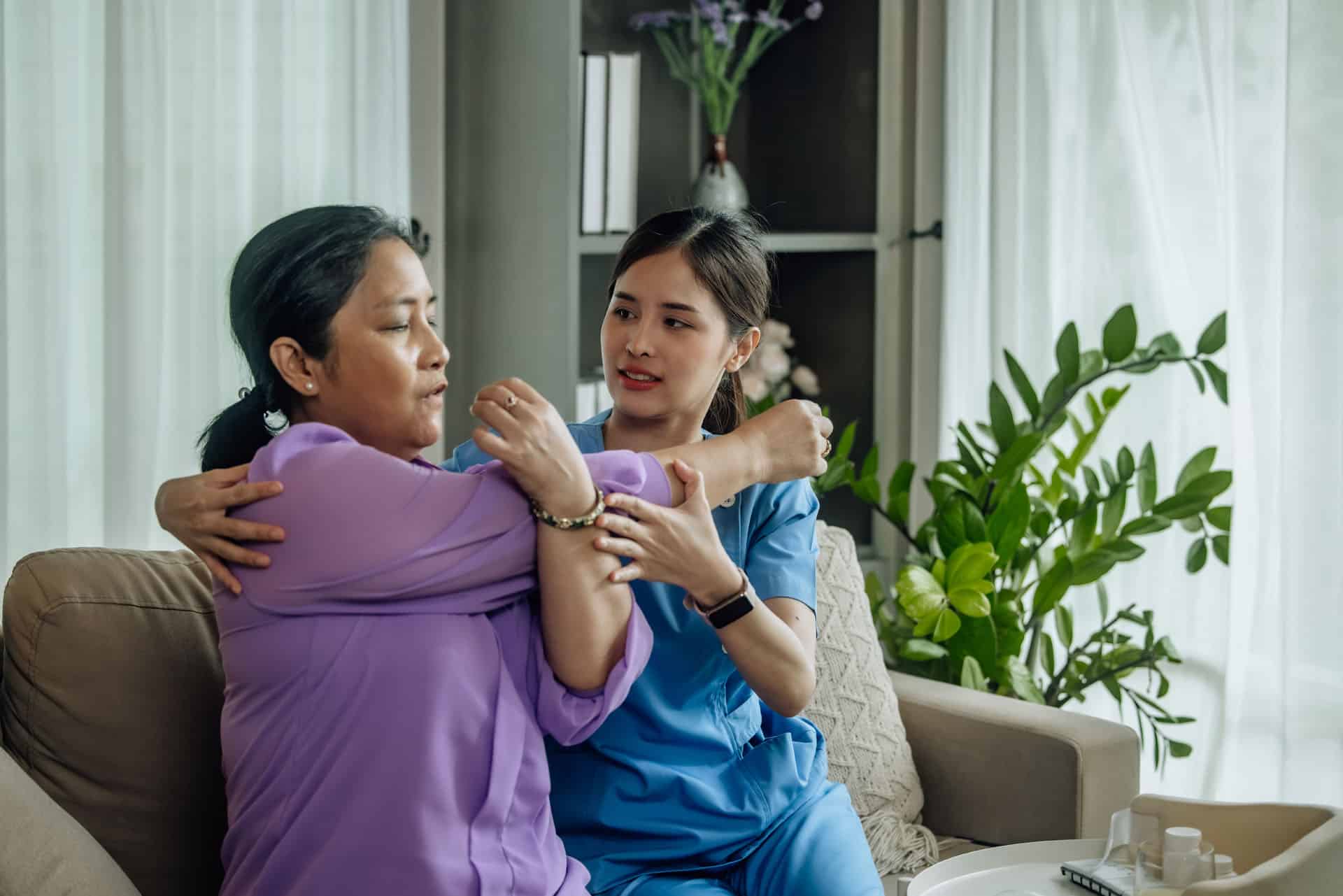 Therapist supporting an individual with movement and daily living skills in a home setting.