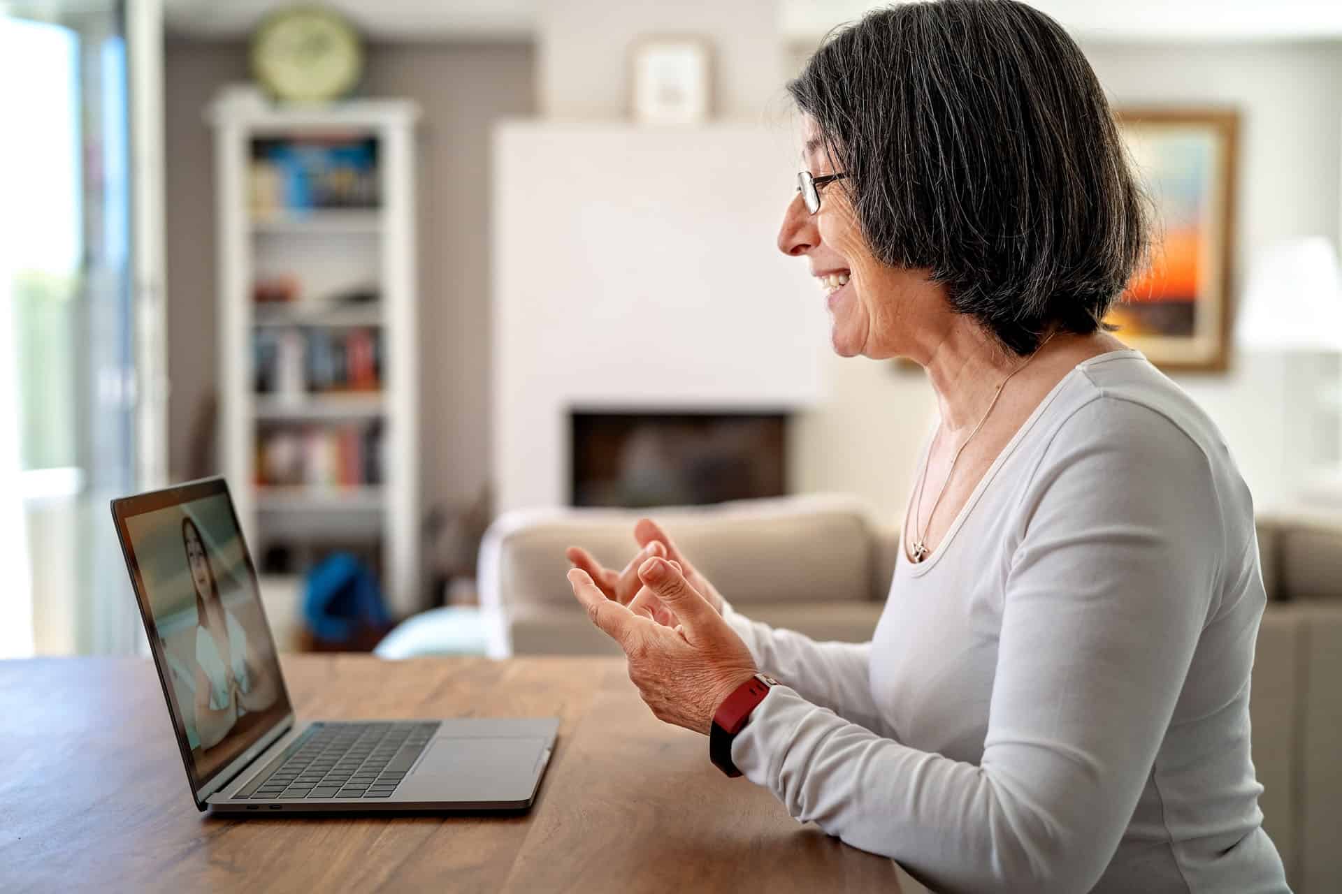 Older adult participating in a secure telehealth therapy session from home using a laptop for a virtual appointment with a licensed therapist.